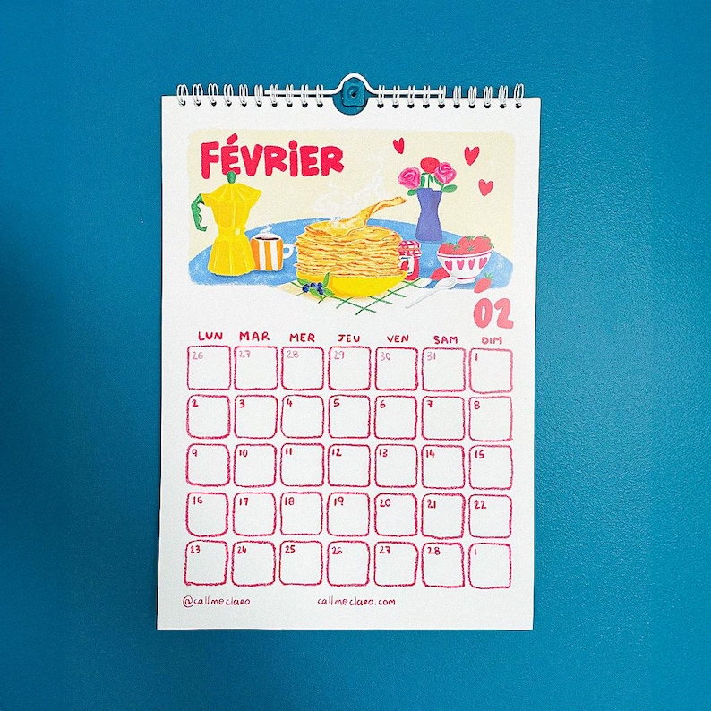 Op de afbeelding: Een spiraalgebonden kalender voor februari met een kleurrijke illustratie van ontbijt. Het woord "F&Eacute;VRIER" staat bovenaan. De kalendergrid is rood, met de dagen van de week in het Frans. Onderaan staat "@callmeclaro" en "callmeclaro.com".