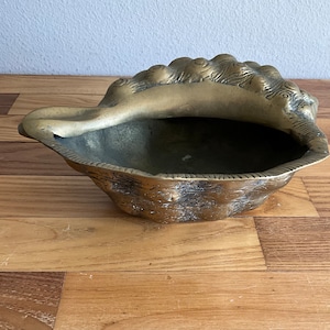 Peut inclure: Un bol en laiton en forme de coquillage avec des détails complexes. Le bol est vide et a une surface lisse et polie.