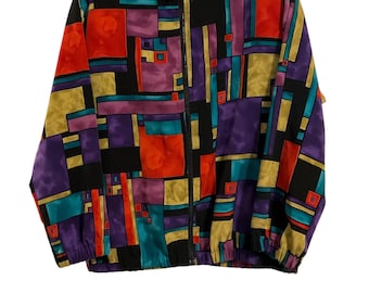 Puede incluir: Chaqueta vintage con cremallera y un vibrante estampado geométrico en rojo, naranja, turquesa, morado, amarillo y negro. La chaqueta tiene cuello alto y puños y dobladillo elásticos. La marca "Drapers & Damon" es visible en el cuello.