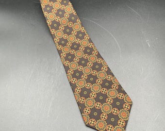 May include: A brown tie with a repeating pattern of orange, yellow, and green floral and checkered designs. The tie is made of a smooth fabric and is suitable for formal or business attire.