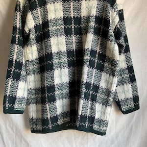 May include: A green, white, and pink plaid sweater with a crew neck.