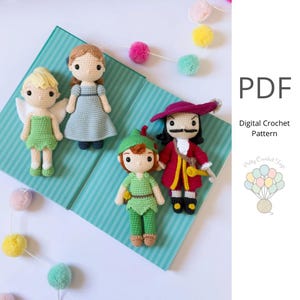 May include: Four handmade crochet dolls of characters from Peter Pan. The dolls include Tinkerbell with wings, Wendy in a blue dress, Peter Pan in green, and Captain Hook in a red coat. The dolls are on a blue surface with the text "PDF Digital Crochet Pattern".