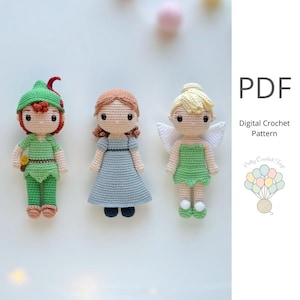 Pode incluir: Três bonecas de crochê feitas à mão: Peter Pan em verde, Wendy com um vestido azul e Sininho em verde com asas brancas. As bonecas estão em um fundo branco. A imagem também inclui o texto "PDF Digital Crochet Pattern".