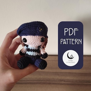 May include: Crochet pattern PDF for a small amigurumi figure wearing a blue beret, a striped shirt, and blue pants. The pattern is available for download and includes instructions for making the figure. The PDF is from the shop "lubi crochet".