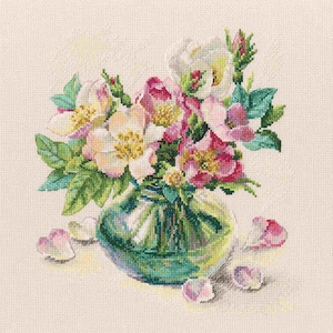 Op de afbeelding: Een boeket roze en witte rozen met groene bladeren in een glazen vaas. De vaas staat op een wit oppervlak.