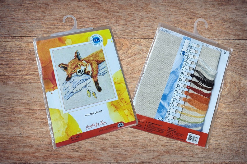 May include: A cross-stitch kit featuring a sleeping fox on a branch with autumn leaves. The kit includes a piece of Aida cloth, floss, and instructions. The packaging is labelled "Autumn Dream" and "Create for Fun".