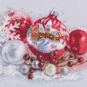 May include: A red Christmas ornament with a white house design and snowflakes. The ornament is surrounded by white snowflakes and red berries.
