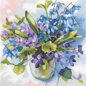 May include: Cross-stitch design of a floral bouquet in a clear vase. The flowers are a mix of blue and purple, with green leaves. The background is a light blue and white, with a touch of pink.