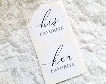 Op de afbeelding: Twee witte ronde stickers met zwarte tekst. De bovenste sticker zegt "zijn favoriet" en de onderste sticker zegt "haar favoriet".