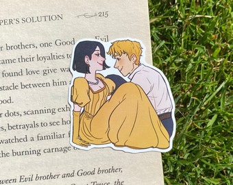 May include: A sticker featuring a couple embracing. The woman is wearing a yellow dress with a pearl necklace and the man is wearing a white shirt. The sticker is on a book with the text "KEEPER'S SOLUTION" and "Evil" visible.