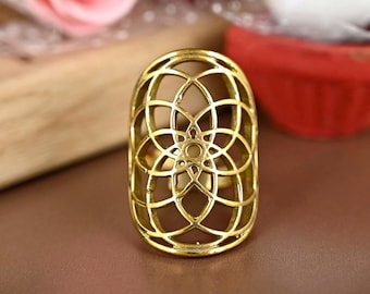 Puede incluir: Un anillo de color dorado con un diseño geométrico. El anillo tiene forma ovalada y presenta un patrón delicado e intrincado.