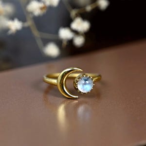 Può includere: Un anello d'oro con un design a forma di mezzaluna e una pietra di luna rotonda.
