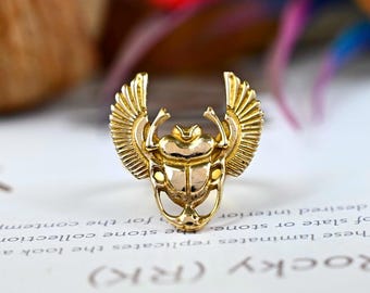 May include: A gold-coloured scarab beetle with wings, a popular symbol of ancient Egypt.