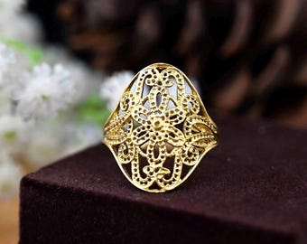 Puede incluir: Un anillo de filigrana dorada con un delicado diseño floral. El anillo tiene forma ovalada y presenta un patrón detallado e intrincado.