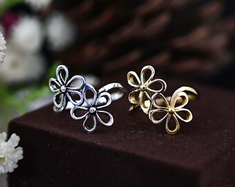 May include: Two adjustable rings with a three-flower design. One ring is silver and the other is gold.