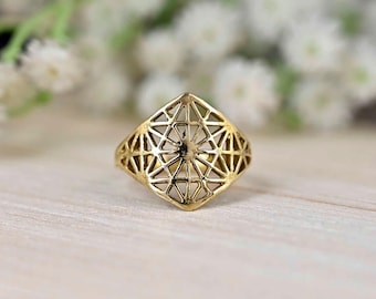 Puede incluir: Un anillo de oro con un diseño geométrico. El anillo está hecho de un patrón delicado e intrincado de triángulos y cuadrados.