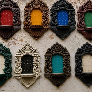 May include: A collection of eight wall-mounted arched shelves featuring ornate carved frames in various colours including brown, black, green, and cream. Each shelf has a central fabric panel with a small white polka dot pattern and a small ledge.