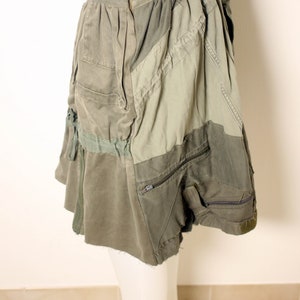 May include: A green patchwork skirt with a zipper closure and multiple pockets. The skirt is made of a variety of fabrics, including denim and canvas.