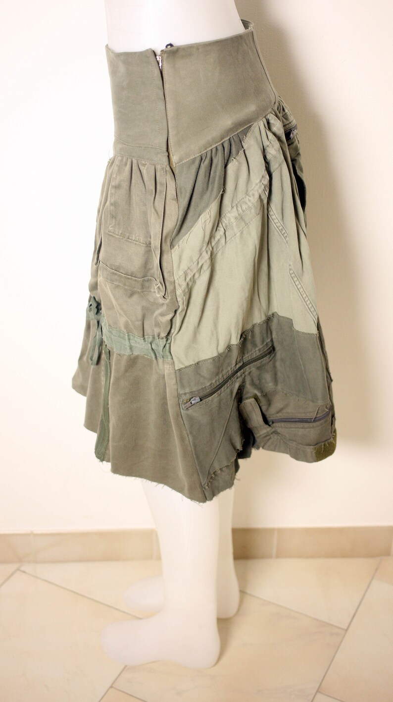 May include: A green patchwork skirt with a zipper closure and multiple pockets. The skirt is made of a variety of fabrics, including denim and canvas.