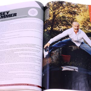Puede incluir: Una p&aacute;gina de revista con un art&iacute;culo sobre Kelsey Grammer. La p&aacute;gina de la derecha muestra una foto de Grammer saltando en el aire, vistiendo una camisa blanca, vaqueros azules y zapatos blancos. Se ve un peque&ntilde;o cubo rojo.