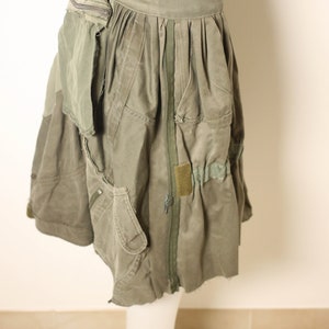 May include: A green utility skirt with multiple pockets and a zipper down the front. The skirt is made of a thick, durable fabric and has a relaxed fit.