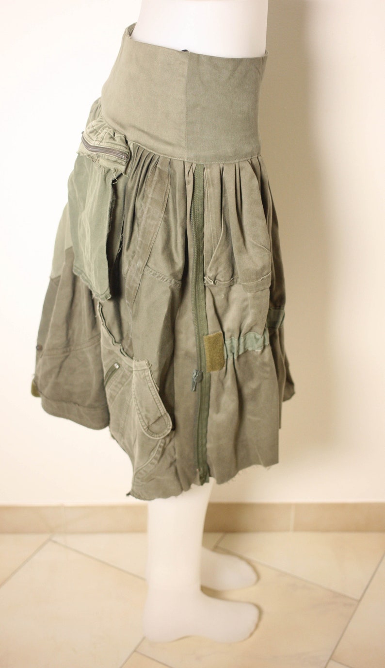 May include: A green utility skirt with multiple pockets and a zipper down the front. The skirt is made of a thick, durable fabric and has a relaxed fit.