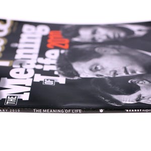 Puede incluir: Revista Esquire, n&uacute;mero de enero de 2010, con el titular "The Meaning of Life". La portada es negra con texto blanco y rojo, y presenta retratos de figuras hist&oacute;ricas. La revista est&aacute; sobre una superficie blanca.