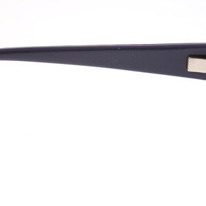 May include: Dark blue eyeglasses with a rectangular frame and a silver hinge. The temple arm is marked with text. The lenses are clear. The glasses are set against a white background.
