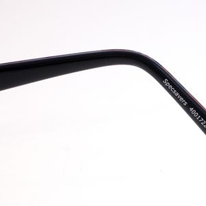 May include: A close-up of a black glasses arm, featuring the text "Specsavers 4001722 CE P83". The arm has a curved design and a shiny surface. The background is a simple white.