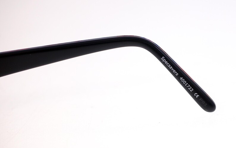 May include: A close-up of a black glasses arm, featuring the text "Specsavers 4001722 CE P83". The arm has a curved design and a shiny surface. The background is a simple white.
