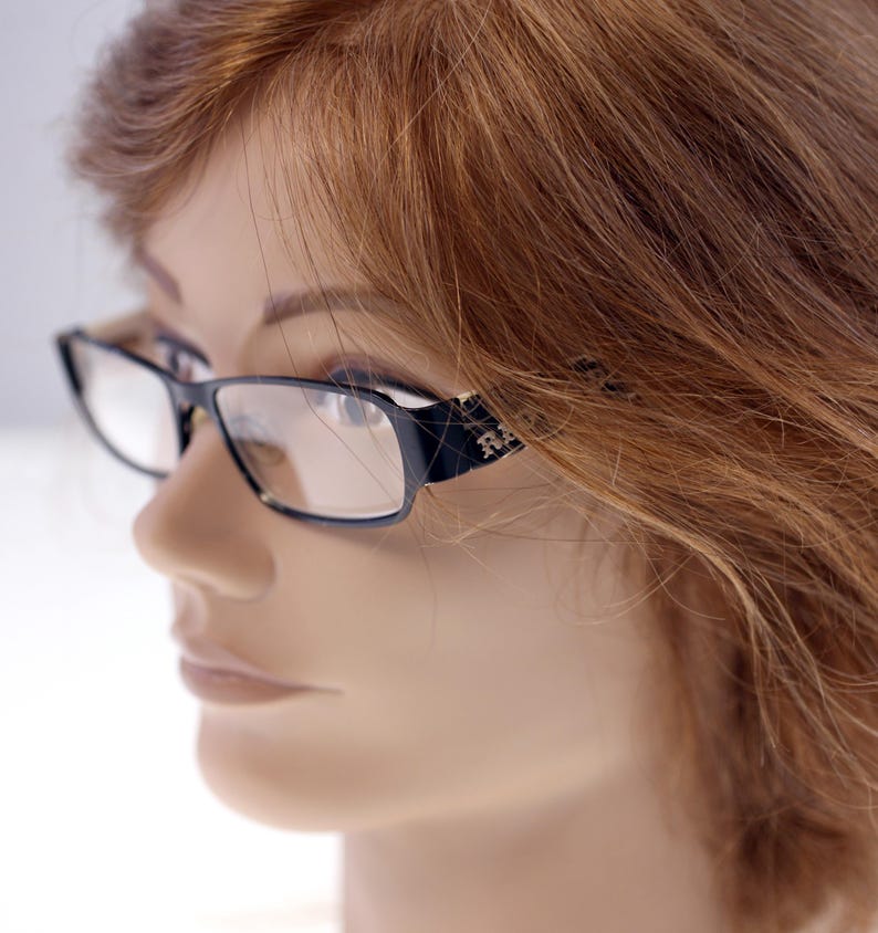 May include: Black rectangular eyeglasses with clear lenses. The frames feature a subtle design on the temples. The glasses are set against a neutral background, highlighting their sleek, modern design. Suitable for everyday use.