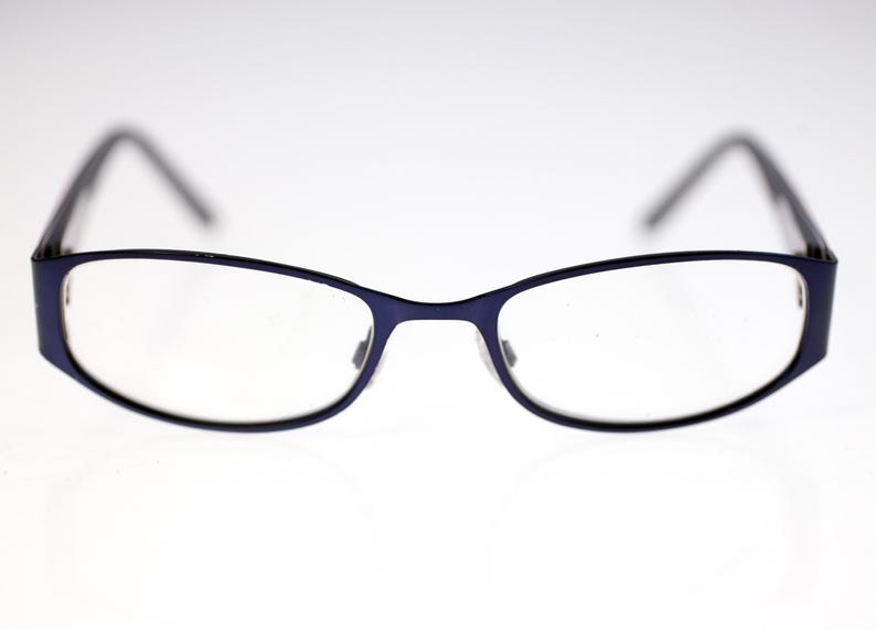 May include: Eyeglasses with a dark blue frame and clear lenses. The glasses have a rectangular shape with rounded edges. The temples are black. The glasses are designed for vision correction.