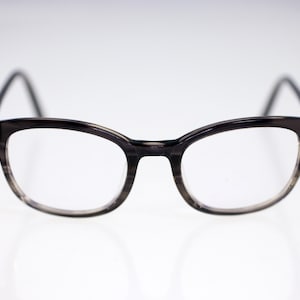 Może przedstawiać: Okulary w szarym kolorze z prostokątną oprawką i przezroczystymi szkłami.