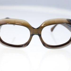 May include: A pair of brown plastic framed glasses with a rounded, oval shape.