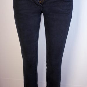 Peut inclure: Jean en denim bleu marine foncé avec fermeture à bouton et fermeture éclair. Le jean a une conception classique à cinq poches et une coupe droite. Le tissu semble être un denim de poids moyen.