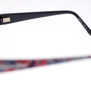 May include: Eyeglasses with a dark blue frame and patterned temples. The temples display a colourful pattern of red, blue, and white. The text "Specimens 4001722 CE" is printed on the temple.