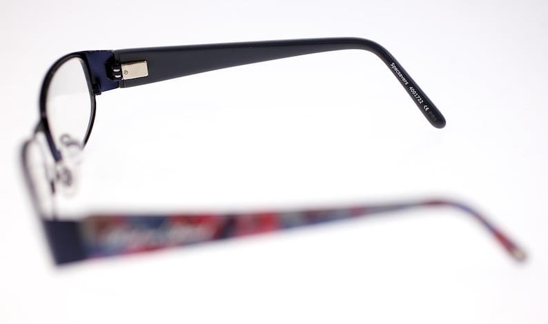 May include: Eyeglasses with a dark blue frame and patterned temples. The temples display a colourful pattern of red, blue, and white. The text "Specimens 4001722 CE" is printed on the temple.