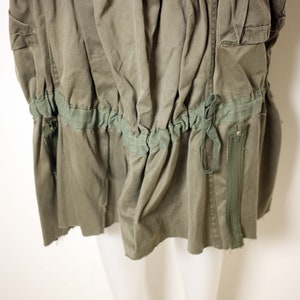 May include: A green utility skirt with a drawstring waist and a zipper on the side. The skirt is made of a durable, lightweight fabric.