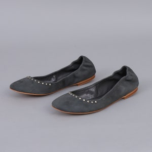 May include: A pair of gray suede ballet flats with silver studs around the toe and heel.