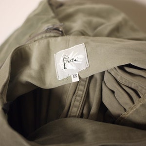 May include: A green utility jacket with a white label that says "Free People" and "XS".