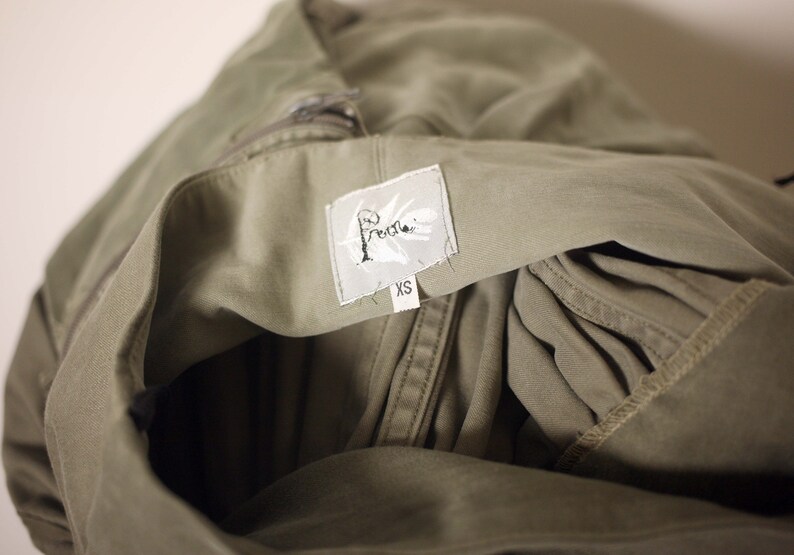 May include: A green utility jacket with a white label that says "Free People" and "XS".