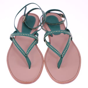 May include: A pair of green leather sandals with gold studs. The sandals have a thin strap that wraps around the ankle and a toe thong.