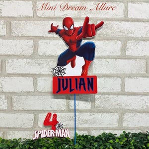 May include: Red and blue Spiderman cake topper with a name tag that says "JULIAN" and a separate topper that says "SPIDER-MAN" with the number 4.