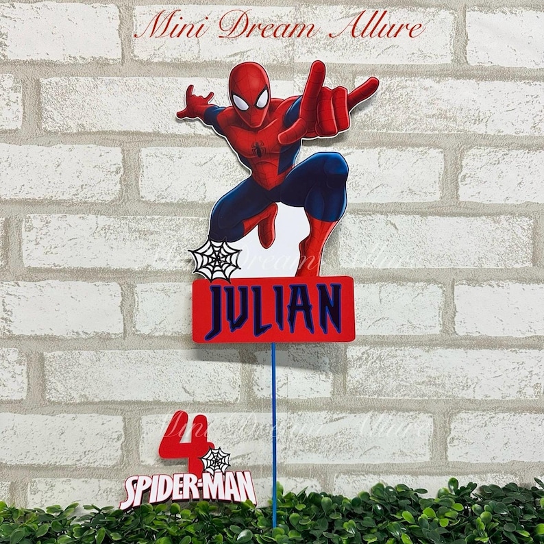 May include: Red and blue Spiderman cake topper with a name tag that says "JULIAN" and a separate topper that says "SPIDER-MAN" with the number 4.