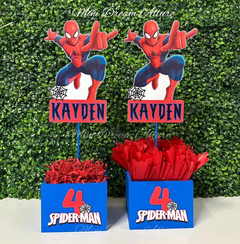 May include: Two blue and red centerpieces with the name "Kayden" and the number "4" on them. The centerpieces feature a Spiderman character and the text "Spider-Man".