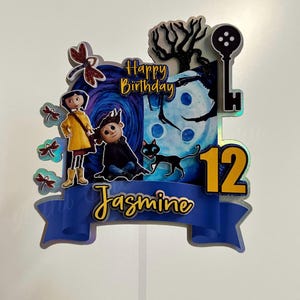 Puede incluir: Un adorno para pastel azul y amarillo con una pancarta azul que dice "Jasmine" y el n&uacute;mero "12". El adorno presenta personajes de la pel&iacute;cula "Coraline" con el texto "Feliz cumplea&ntilde;os".