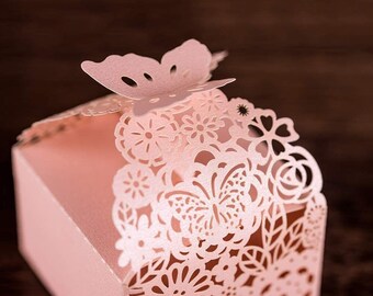 Peut inclure: Une boîte à dragées décorative rose avec un motif de papillon. La boîte est faite de papier délicat découpé au laser et présente un motif floral.