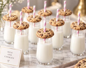 May include: A collection of clear glass tumblers filled with white milk, each topped with a round chocolate chip cookie and a pink and white striped paper straw. A small white card with gold trim displays the text MILK AND COOKIES with a heart.