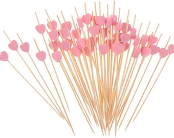 May include: A bunch of wooden skewers with pink heart-shaped toppers. The skewers are arranged in a fan shape.