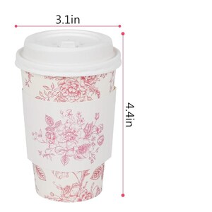 May include: A disposable coffee cup with a white lid and floral design. The cup is 11.2 cm tall and 7.9 cm wide. The floral pattern is in shades of red and pink.